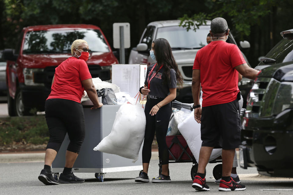 College students with the assistance of their families begin moving in for the fall semester at N.C. State University in Raleigh, N.C., Friday, July 31, 2020. The first wave of college students returning to their dorms aren’t finding the typical mobs of students and parents. At N.C. State, the return of students was staggered over 10 days and students were greeted Friday by socially distant volunteers donning masks and face shields. (AP Photo/Gerry Broome)