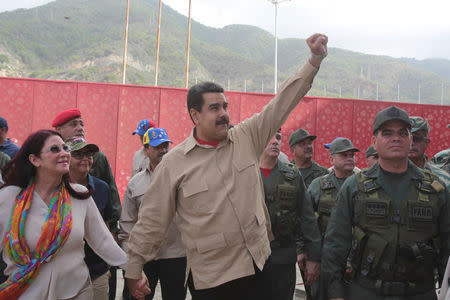 Venezuela's President Nicolas Maduro (C) greets supporters as he arrives to a military parade, next to his wife and deputy of Venezuela's United Socialist Party (PSUV) Cilia Flores (L) and Venezuela's Defense Minister Vladimir Padrino Lopez (R) in La Guaira, Venezuela May 21, 2016. Miraflores Palace/Handout via REUTERS
