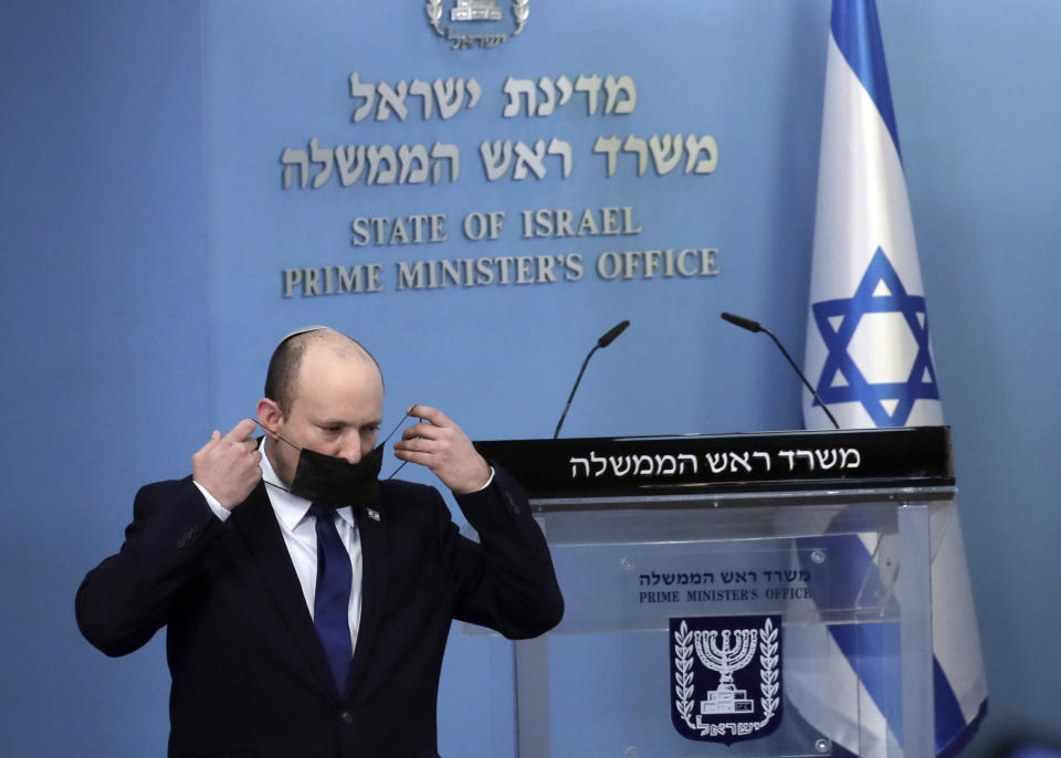 Israel's Prime Minister Naftali Bennett puts on a face mask used as a protective against the coronavirus after delivering a statement in Jerusalem, Wednesday, July 14, 2021. Bennett said Wednesday that Israel can beat a concerning rise in new coronavirus cases without a nationwide shutdown, but he called on people to wear masks indoors and otherwise comply with safety rules. (AP Photo/Maya Alleruzzo)