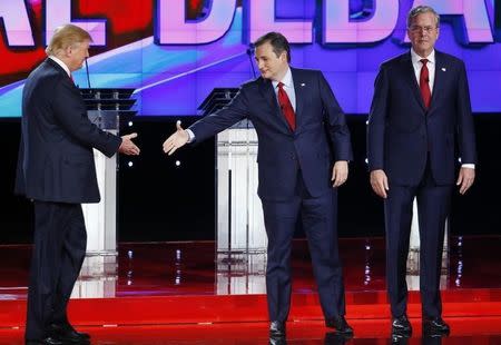 Republican U.S. presidential candidate businessman Donald Trump (L) reaches out to shake hands with Senator Ted Cruz as former Governor Jeb Bush (R) stands beside Cruz before the start of the Republican presidential debate in Las Vegas, Nevada December 15, 2015. REUTERS/Mike Blake