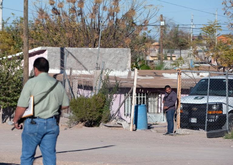 Police stand guard at a house in which eight members of a family were killed by gunmen in Ciudad Juarez, Mexico, on November 17, 2013