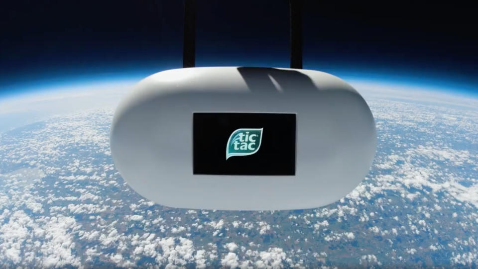 A giant electronic Tic Tac floating through space, above Earth.