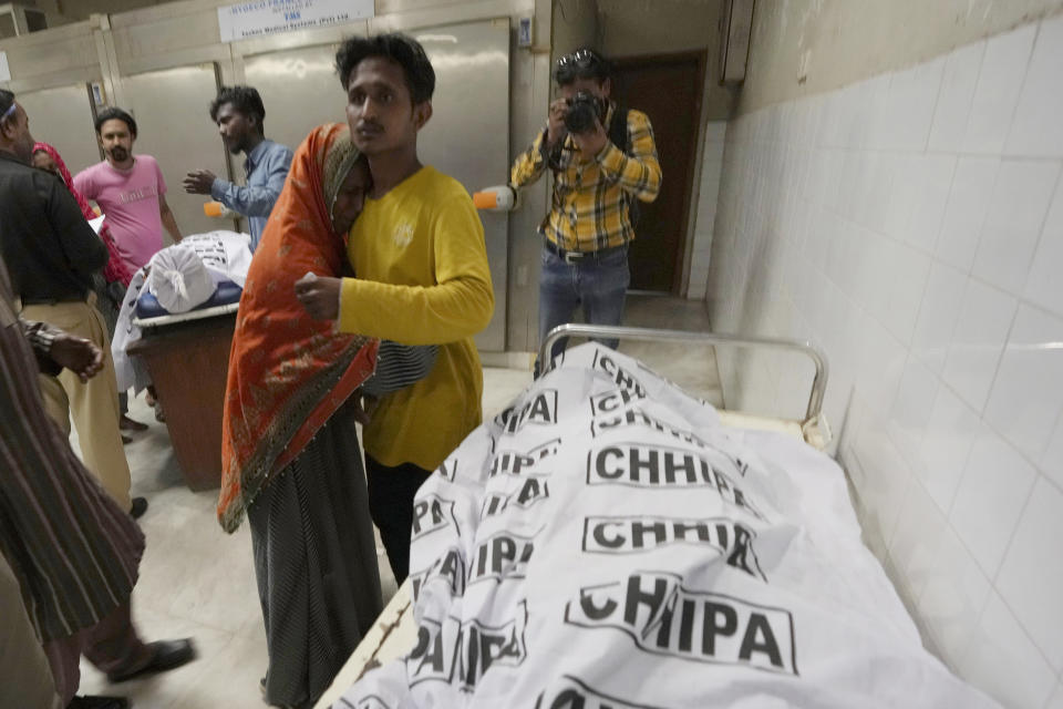 People mourn next to the body of their family member, who was died in the stampede, at a morgue, in Karachi, Pakistan, Friday, March 31, 2023. Several people were killed in the deadly stampede at a Ramadan food distribution center outside a factory in Pakistan's southern port city of Karachi, police and rescue officials said. (AP Photo/Fareed Khan)