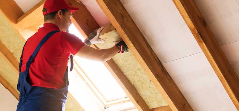 Man installing insulation in an attic.