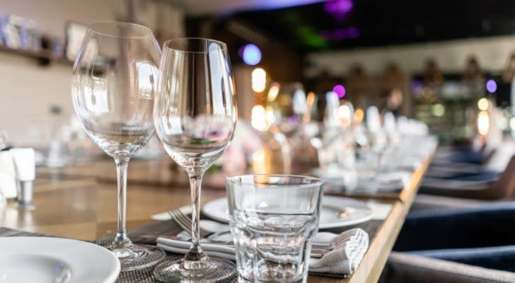 restaurant stocks: wine glasses, cutlery and plates on a long table