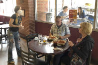 Anna Barnard, left, wears a protective mask as she talks to Greg and Judy Robinson at Dugan's Pub in Little Rock, Arkansas on Monday, May 11,2020. Restaurants in Arkansas were allowed to resume offering dine-in service on Monday after they had been limited to delivery or carryout because of the coronavirus pandemic. (AP Photo/Andrew DeMillo)