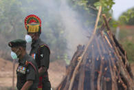 Indian army officers wearing masks as a precaution against the coronavirus walk past the funeral pyre of their colleague Colonel B. Santosh Babu, at Suryapet, about 140 kilometers (87.5 miles) from Hyderabad, India, Thursday, June 18, 2020. Babu was among the twenty Indian troops who were killed in the clash Monday night that was the deadliest conflict between the sides in 45 years. India on Thursday cautioned China against making "exaggerated and untenable claims" to the Galvan Valley area even as both nations tried to end a standoff in the high Himalayan region where their armies engaged in a deadly clash. (AP Photo/Mahesh Kumar A.)