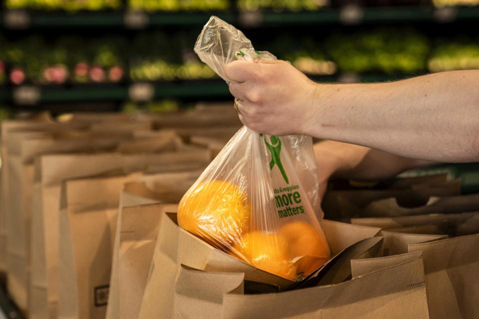 <span>A worker selects oranges for a customer order at an Amazon Fresh grocery store in Seattle, Washington, last month.</span><span>Photograph: David Ryder/Bloomberg via Getty Images</span>