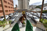 Father Jonathan Gonzalez celebrates a drive-in Sunday Mass set up to circumvent the regulations that prevent concentrations in religious temples, imposed since March by the authorities to curb the spread of the new coronavirus, at the parking lot of the "Nuestra Señora de Coromoto" church in the El Paraiso neighborhood of Caracas, Venezuela, Sunday, Oct. 25, 2020. (AP Photo/Matias Delacroix)