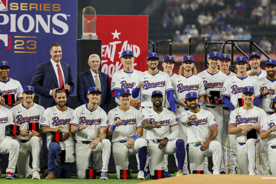 Texas Rangers players, coaches and the owner pose together after receiving their World Series rings before a baseball game against the Chicago Cubs, Saturday, March 30, 2024, in Arlington, Texas. (AP Photo/Gareth Patterson)
