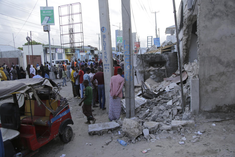 Somalis stand outside the destroyed Pearl Beach hotel in Mogadishu, Somalia , Saturday, June 10, 2023. Witnesses and state media in Somalia say extremists have attacked the beachside hotel in the capital, Mogadishu, and security forces are responding at the site as some people remain trapped inside.(AP Photo/Farah Abdi Warsameh)