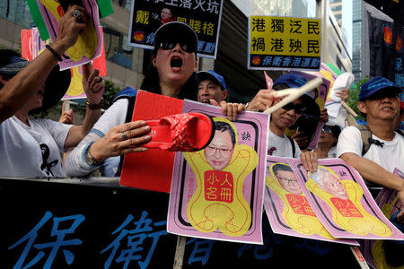 A protester against Occupy Central founder Benny Tai chants slogans while using a sandal to hit a photo of him outside a district court in Hong Kong September 19, 2017. REUTERS/Bobby Yip