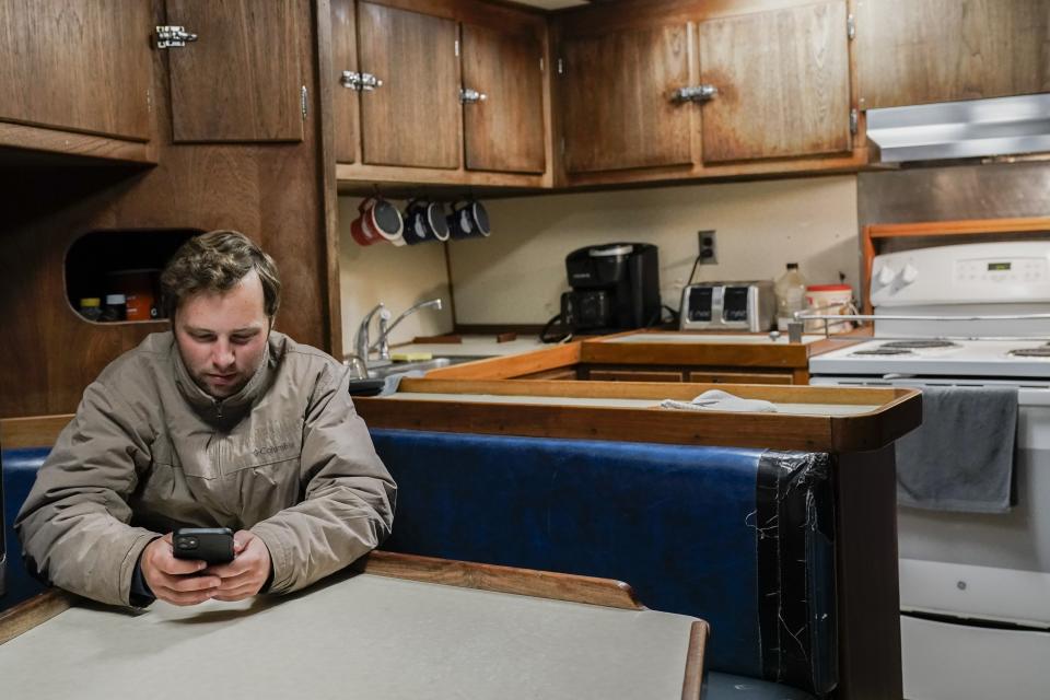 Sam Stern checks his phone while relaxing inside the a fishing boat's galley, Monday, June 26, 2023, in Kodiak, Alaska. Stern, a deckhand on the Big Blue, plans to pursue a career in marine engineering and worked this season to both make money for school and to earn hours at sea for eventual licensing he'll need for that job. (AP Photo/Joshua A. Bickel)