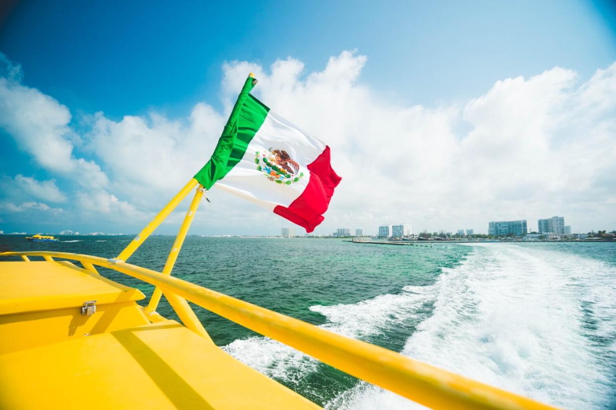 Cancun is a popular and safe destination of Mexico. pictured: a Mexican flag on the tail end of a boat off the coast of Cancun