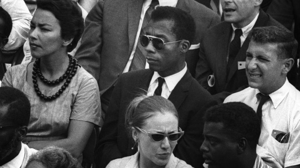 Black-and-white shot of James Baldwin, center, in a crowd in "I Am Not Your Negro."