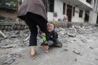 RNPS - PICTURES OF THE YEAR 2013 - A boy holds his mother's leg as he cries in front of their damaged house after a strong 6.6 magnitude earthquake at Longmen village, Lushan county in Ya'an, Sichuan province April 21, 2013. Rescuers poured into a remote corner of southwestern China on Sunday as the death toll from the country's worst earthquake in three years climbed to 164 with more than 6,700 injured, state media said. REUTERS/Jason Lee (CHINA - Tags: DISASTER ENVIRONMENT TPX)