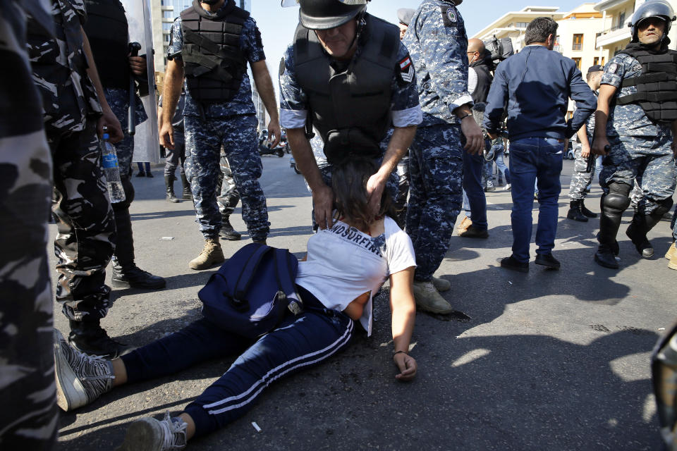 A riot police helps a fainted anti-government protester and tries to pull her out, as other policemen open a road in Beirut, Lebanon, Thursday, Oct. 31, 2019. Army units and riot police took down barriers and tents set up in the middle of highways and major intersections Thursday. (AP Photo/Bilal Hussein)