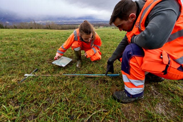 two people taking measurements on the ground