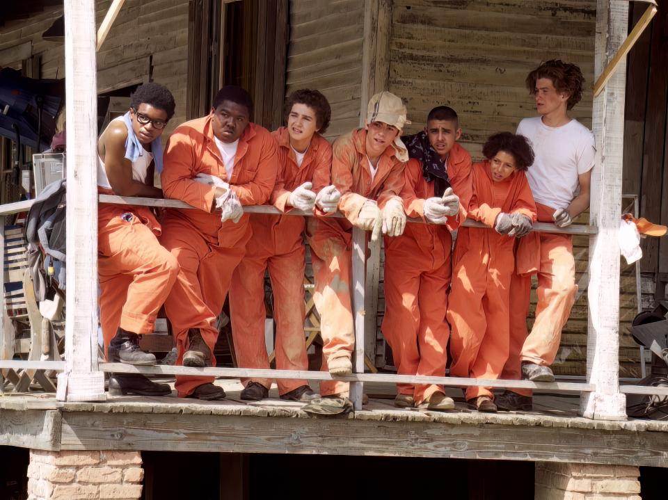 the kids filming a scene in holes in their orange jumpsuits