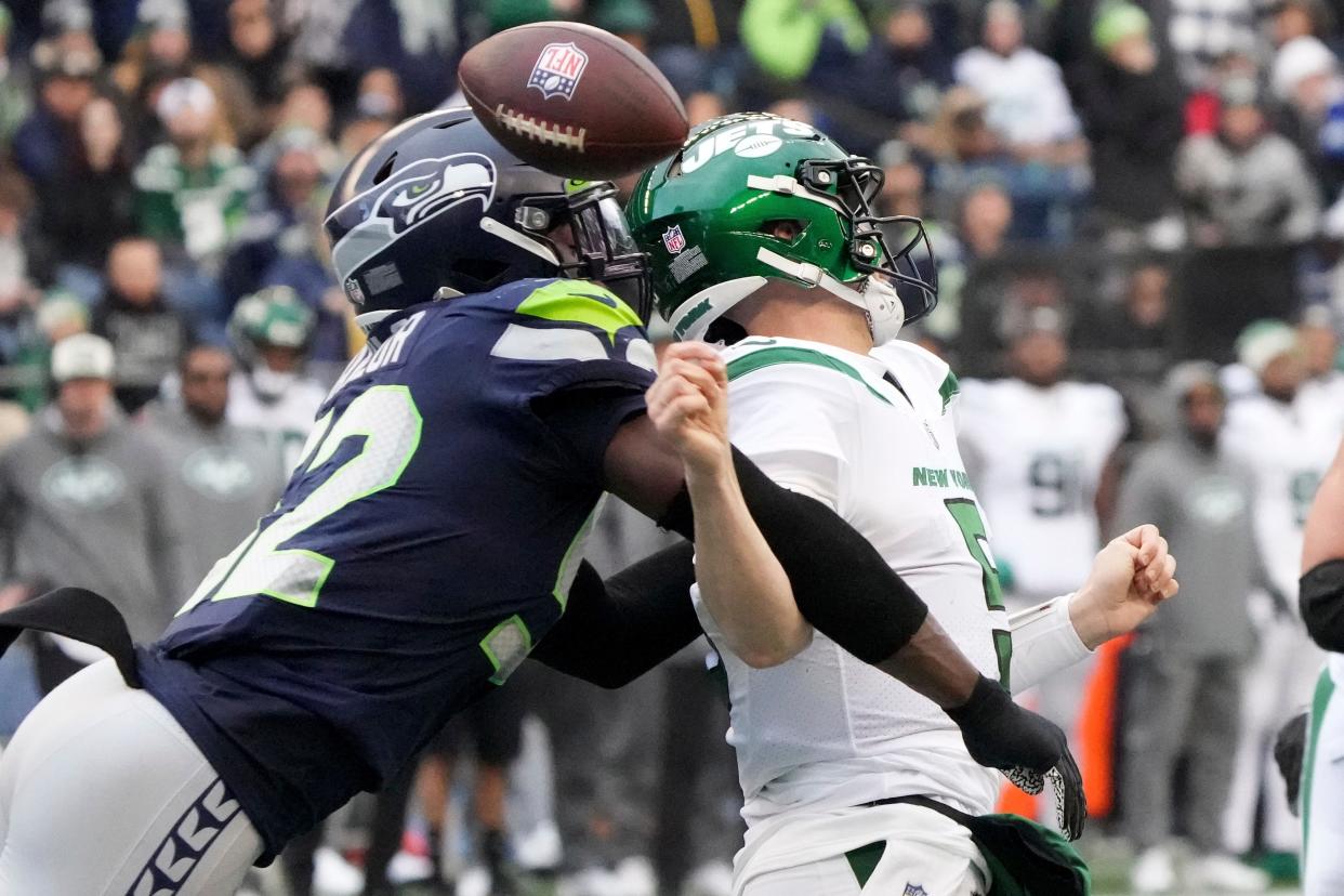 Seattle Seahawks defensive end Darrell Taylor, left, forces New York Jets quarterback Mike White (5) to fumble during the first half Sunday. The Seahawks recovered the ball.