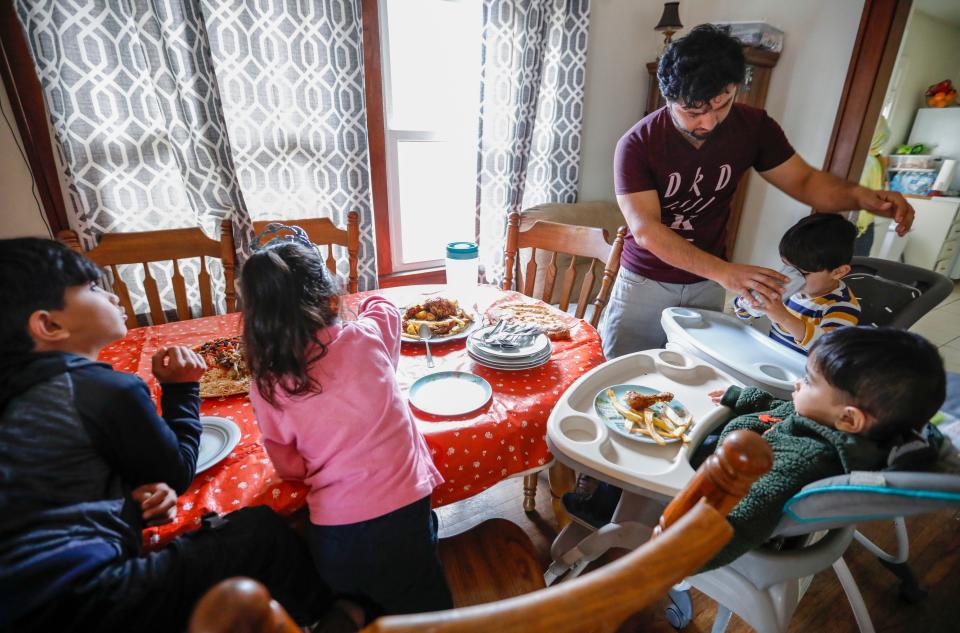 Romal Noori helps his children (from left) 6-year-old Abdul Bais, 6-year-old Behishta, 18-month-old Mohammad Sorosh, and 2-year-old Mohammad Sodais as they sit down for lunch at their home on Saturday, Dec. 17, 2022. Romal Noori worked as a translator for the U.S. military for almost a decade and fled Afghanistan with his family last fall as U.S. troops withdrew and the Taliban took over.