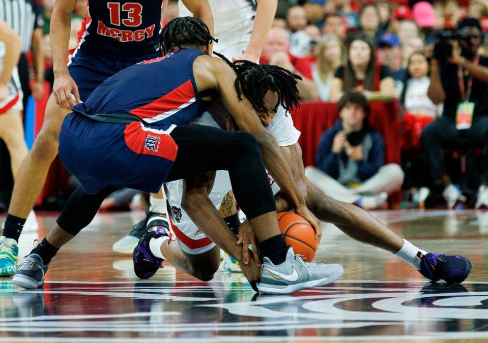 N.C. State’s Jayden Taylor and Detroit’s Marcus Tankersley dive on the floor for a loose ball during the first half of the Wolfpack’s game on Saturday, Dec. 23, 2023, at PNC Arena in Raleigh, N.C.