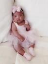 “Baby True! Who is the cutest little munchkin?” Khloé asked her daughter, who was sitting upright on a bed between two pillows while wearing a pale pink ballerina outfit complete with matching tutu, socks and bow.