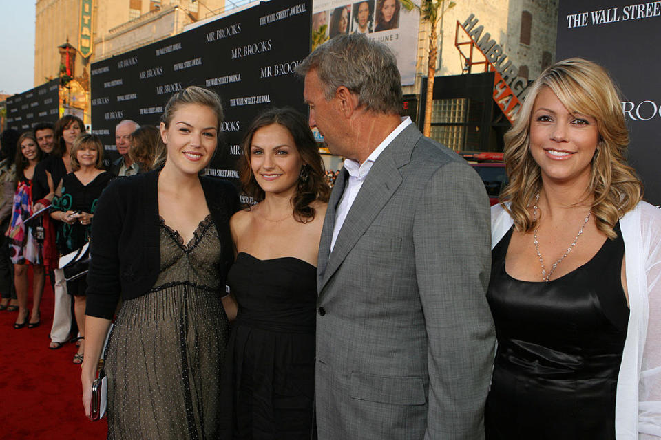 Kevin on the red carpet, looking at his daughters and next to his wife