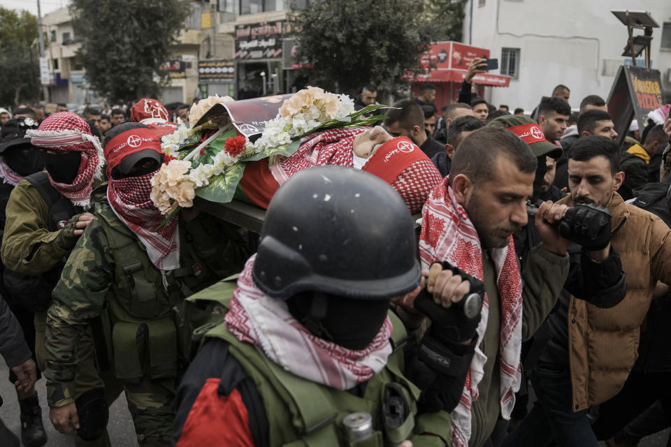 Masked Palestinians carry the body of 14-year-old Omar Khumour during his funeral in the West Bank city of Bethlehem, Monday, Jan. 16, 2023. The Palestinian Health Ministry said Khumour died after being struck in the head by a bullet during an Israeli military raid into Dheisha refugee camp near the city of Bethlehem. The Israeli army said that forces entered the Dheisha camp and were bombarded by Molotov cocktails and rocks. It said soldiers responded to the onslaught with live fire. (AP Photo/Mahmoud Illean)