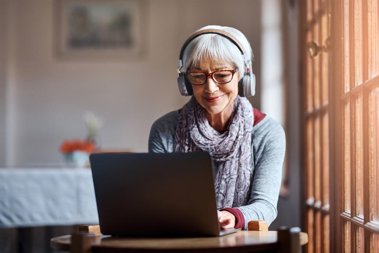 Senior woman on her laptop wearing headphones