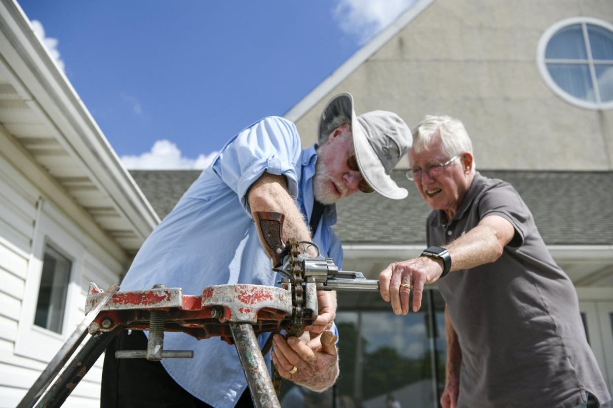 Artist Stephen Canneto, left, and Terry Davis prepare a pistol to be sawed into pieces during the Guns to Gardens event at the First Community Church North on June 11.