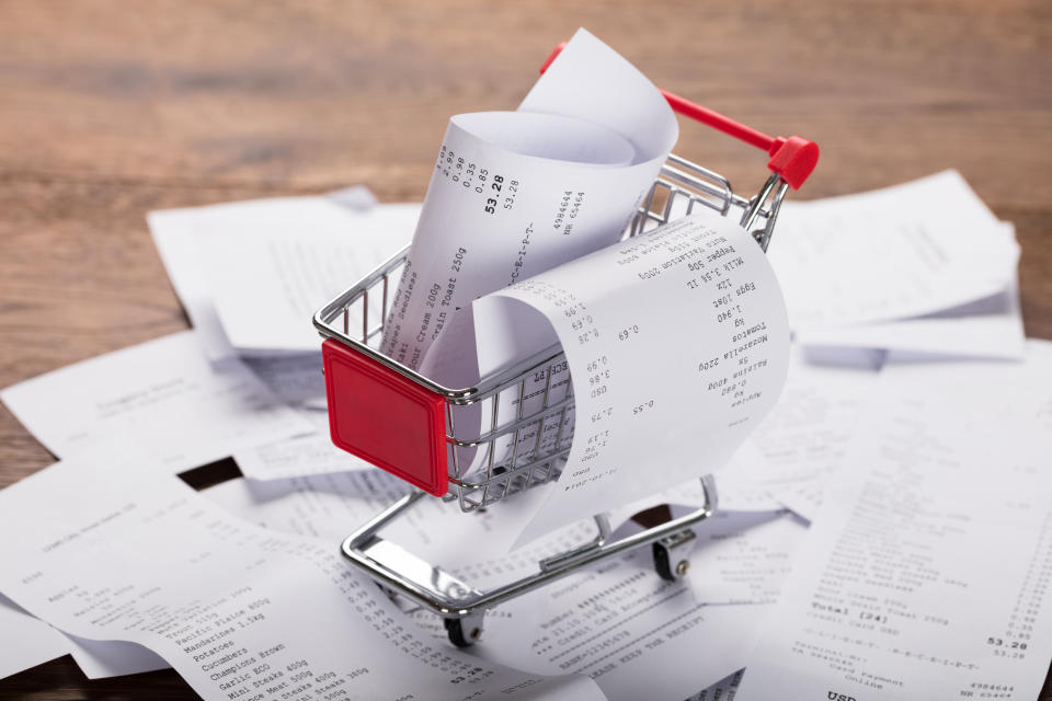 Close-up Of A Shopping Cart With Bunch Of Receipts On Wooden Desk