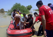Pakistani rescue workers evacuate villagers from flooded areas of Dadu, a district in Pakistan's southern Sindh province, Sunday, Aug. 9, 2020. Pakistan's disaster management agency said three days of heavy monsoon rains that triggered flash floods have killed dozens of people in various parts of the country. (AP Photo/Pervez Masih)