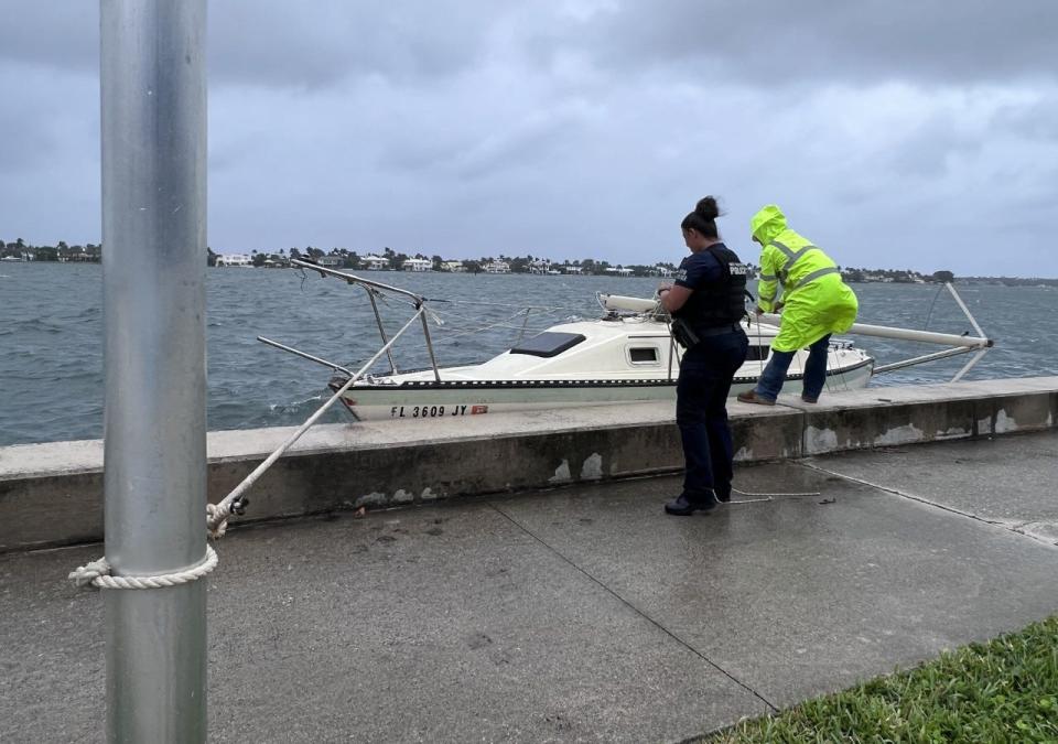 West Palm Beach Police officer helps secure a boat to a street sign after it broke lose Wednesday morning Nov. 9, 2022 as Tropical Storm Nicole approaches Florida.