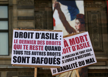 Migrants hold placards which read "Right of asylum, the last of the rights you have when all your other rights are violated" and "Death of the right to asylum" during a demonstration against a new "migration-asylum bill" by the French government in Paris, France, February 21, 2018. REUTERS/Pascal Rossignol