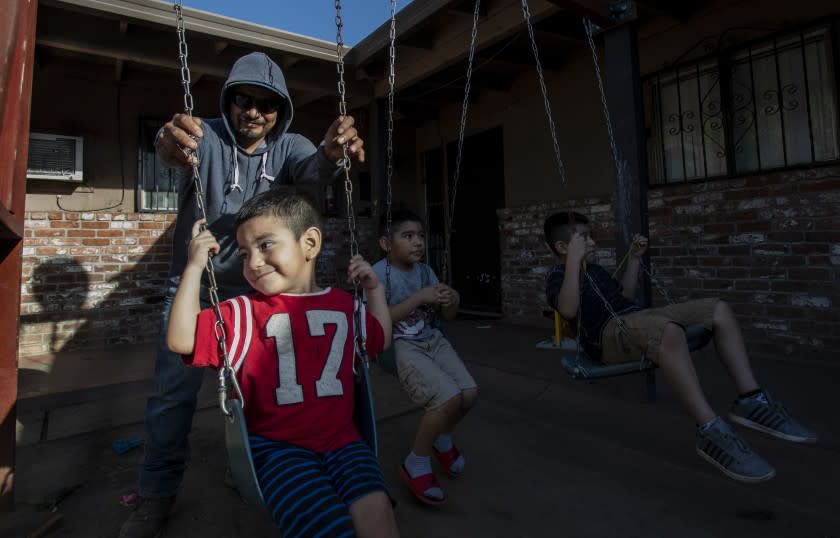 STOCKTON, CA - OCTOBER 14, 2020: Farmworker Jose Luis Hernandez spends time with his sons Carlos, 2, Jose, 6, and Angel,9 outside their apartment on October 14, 2020 in Stockton, California. In normal times, Hernandez would have saved enough money from picking summer fruit in the California fields to make it through the slow winter months, but because of pandemic, his wages were cut and he isn't sure how he will provide food and shelter for his wife and three sons as the final grapes are taken from the vines. He's had to borrow money from a friend."I haven't saved anything. I am worried, " he said.(Gina Ferazzi / Los Angeles Times)