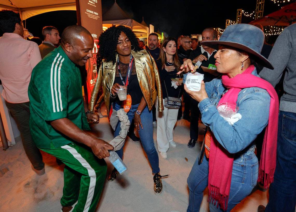 Mark McKenzie and Suzan McDowell dance as Flora Sweet tries out the Night Owl Cookies at the 2024 Burger Bash at the South Beach Wine & Food Festival.
