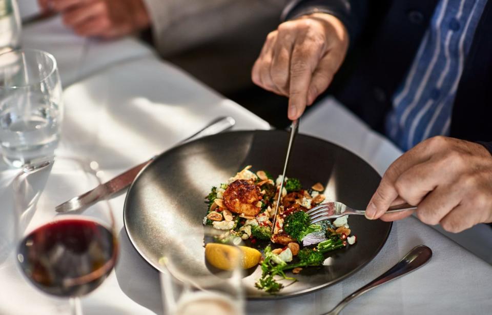 Man cutting food on plate in gourmet restaurant