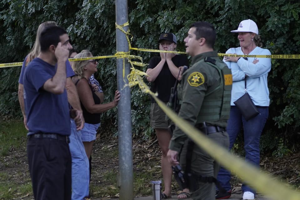 Residents react as they talk to law enforcement personnel about recovering their vehicles outside the taped scene of a mass shooting at Cook's Corner, Thursday, Aug. 24, 2023, in Trabuco Canyon, Calif. (AP Photo/Damian Dovarganes)