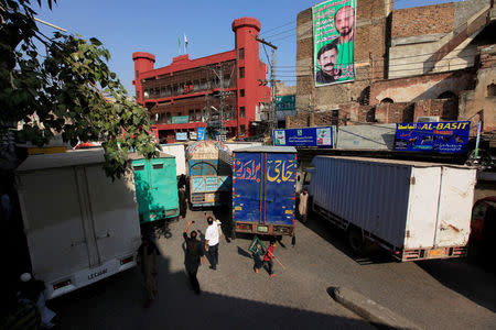 A boy holding a flag walks past trucks, used to block a venue of a planned protest gathering organised by Awami Muslim League, a political ally party of Imran Khan's Pakistan Tehreek-e-Insaf (PTI), in Rawalpindi, Pakistan, October 28, 2016. REUTERS/Faisal Mahmood