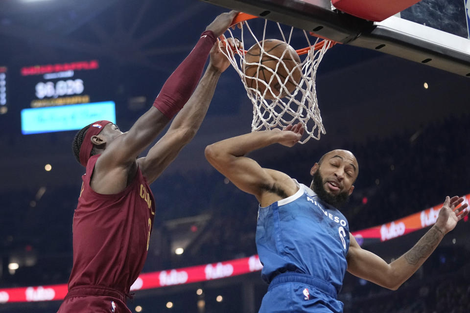 Cleveland Cavaliers guard Caris LeVert, left, dunks over Minnesota Timberwolves guard Jordan McLaughlin during the first half of an NBA basketball game Friday, March 8, 2024, in Cleveland. (AP Photo/Sue Ogrocki)