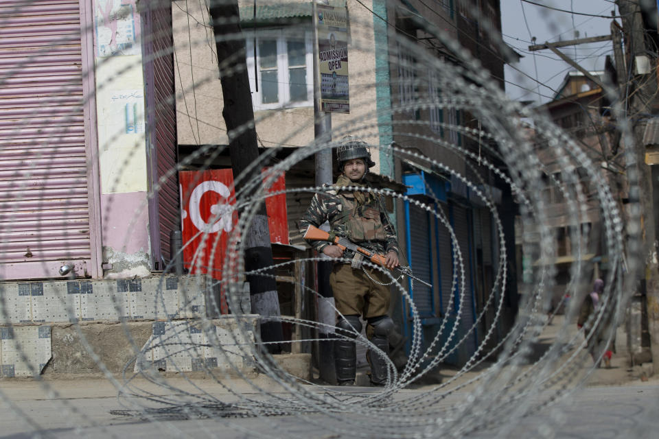 An Indian paramilitary soldier is seen through barbed wire as he stands guard during security lockdown in Srinagar, Indian controlled Kashmir, Sunday, Feb. 24, 2019. Shops and businesses have closed in Kashmir to protest a sweeping crackdown against activists seeking the end of Indian rule in the disputed region. (AP Photo/ Dar Yasin)