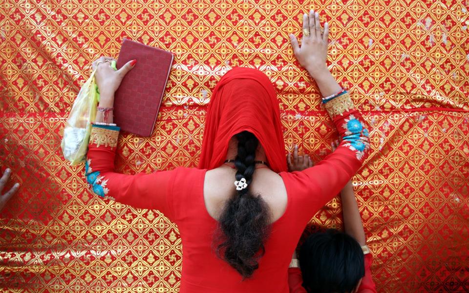 An Indian Hindu devotee prays outside the historical Goddess Kali temple during the Navratri festival in Jammu, the winter capital of Kashmir - Credit: EPA