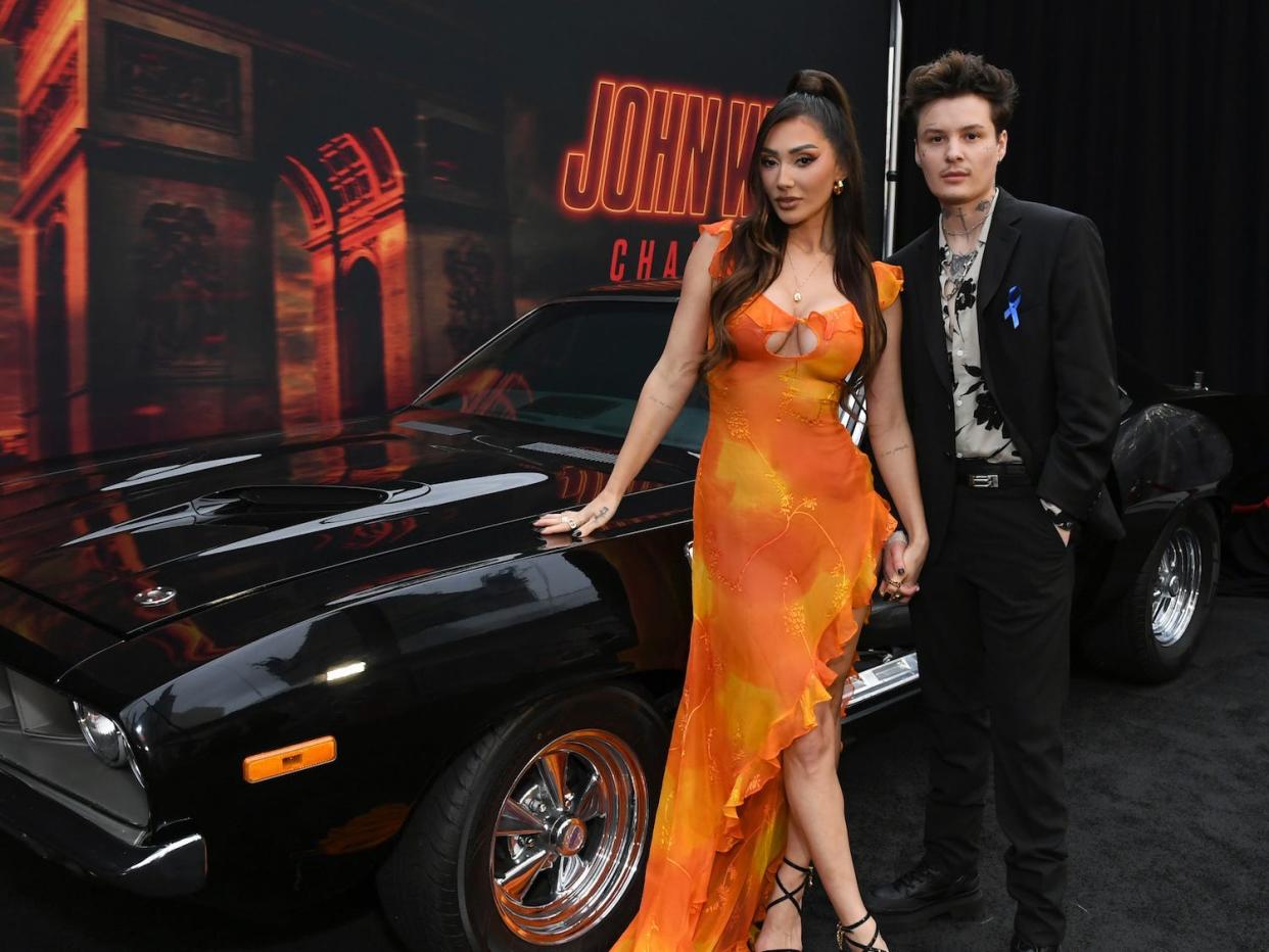 Francesca Farago and Jesse Sullivan standing in front of a car at the John Wick Premiere