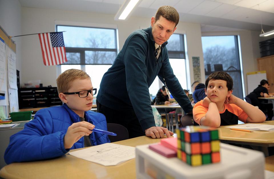 Shane Jackson, a math teacher at the Woodland School in Milford, teaches an MCAS-type problem to a pair of fifth graders, April 7, 2022.