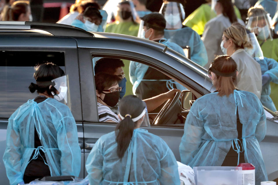 Una familia detiene la marcha de su vehículo en un centro de pruebas gratuitas de COVID-19 desde el auto en el vecindario de Maryvale, en el oeste de Phoenix, Arizona, el sábado 27 de junio de 2020. (AP Foto/Matt York)