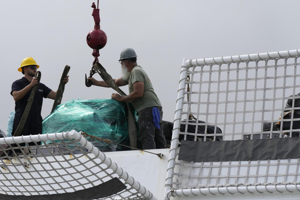 Men attach a palette loaded with bundles of seized cocaine and marijuana to a crane, as the U.S. Coast Guard unloads more than one billion dollars worth of seized drugs from the Coast Guard Cutter James at Port Everglades, Thursday, Feb. 17, 2022, in Fort Lauderdale, Fla. The Coast Guard said the haul included approximately 54,500 pounds of cocaine and 15,800 pounds of marijuana from multiple interdictions in the Caribbean Sea and the eastern Pacific. (AP Photo/Rebecca Blackwell)