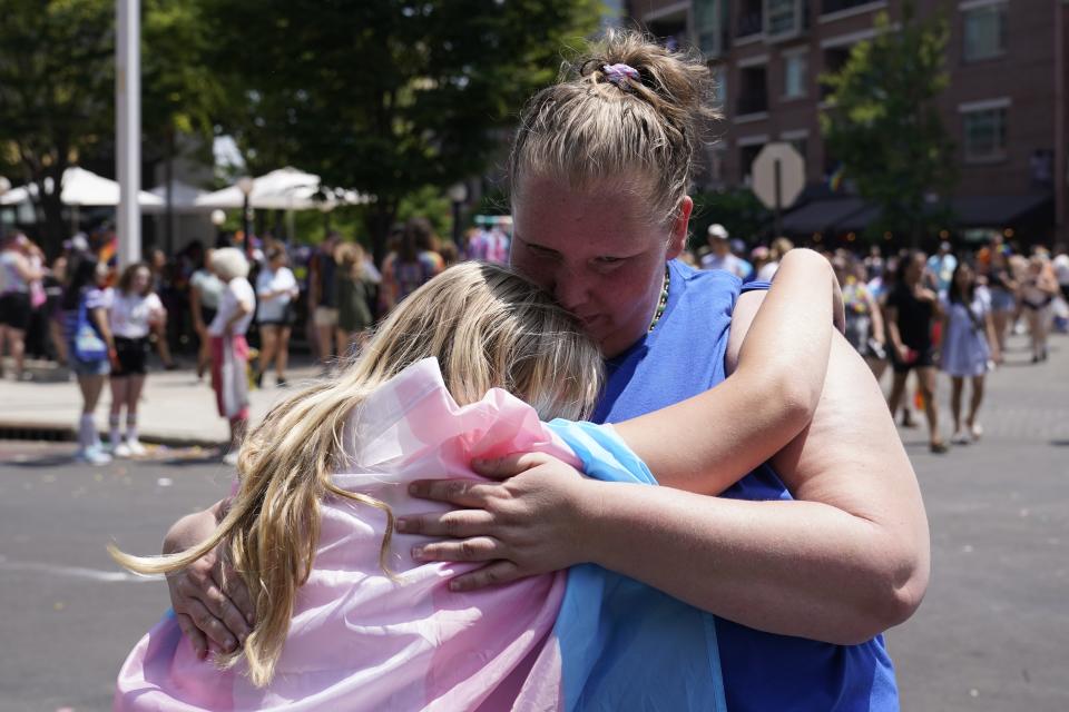 Flower Nichols hugs her mom, Jennilyn Nichols, as they watch the Pride Parade, Saturday, June 10, 2023, in Indianapolis. Families around the U.S. are scrambling to navigate new laws that prohibit their transgender children from accessing gender-affirming care. (AP Photo/Darron Cummings)