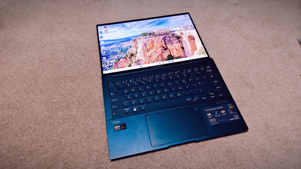 A blue ASUS Zenbook 14 OLED (UX3405) on a carpeted floor