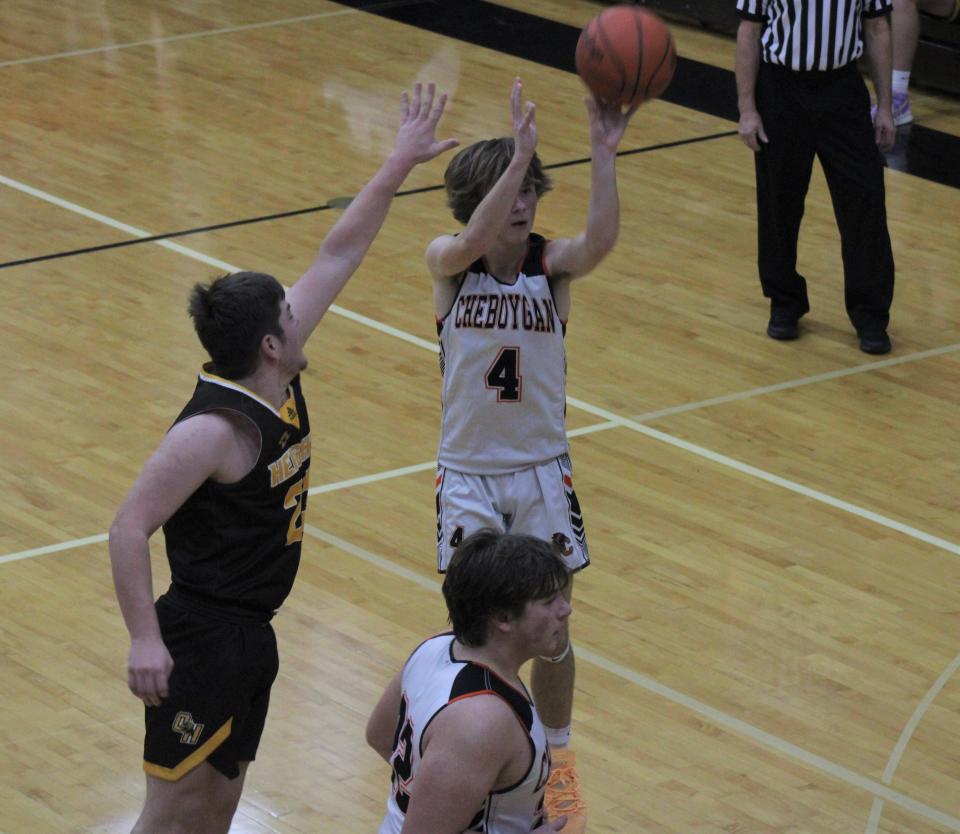 Cheboygan junior guard Kaleb Goodrich (4) puts up a shot over defending Ogemaw Heights senior Quinn Courtemanche (left) during the first half of a varsity boys basketball contest in Cheboygan on Tuesday.